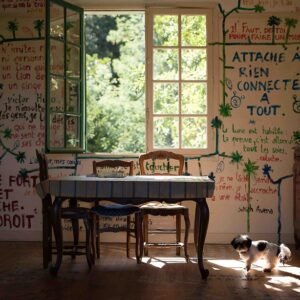 atelier d'artiste urban photography abandonned places Cette photographie d’art humaniste contemporaine représente une pièce semi-abandonnée avec un mobilier ancien et dépareillé, les murs sont entièrement recouverts de citations écrites au pinceau dans des couleurs vert, bleu et rouge. Un petit chien noir et blanc trône dans un rayon de soleil entre la table et le buffet des années 50. C'est l'atelier abandonné de l'artiste Loulou Lalande, peintre du Bassin d'Arcachon. Cette photographie d'art pour décoration murale est disponible en édition limitée numérotée et signée de l'artiste. Ce tirage photo sur papier fine art conviendra particulièrement aux collectionneurs, galeries d'arts et entreprises sensibles au courant urbex, «  abandoned places » et « urban photography ».