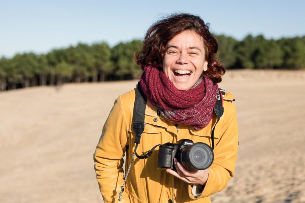 Portrait de l'artiste photographe humaniste Magali Sacau pris en hiver sur la dune du Pyla par Margaret Ales Cowley lors de son passage à Arcachon. L'appareil photo en main et le sourire communicatif.
