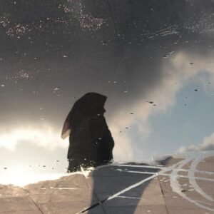 Photographie humaniste du Reflet d'une femme voilée devant un ciel nuageux dans une flaque d'eau sur le quai d'une station balnéaire en Turquie. Dans ce tirage d'art en édition limitée à dix exemplaires l'ombre noire se détache du ciel créant un contraste de couleurs onirique dans des nuances de gris. Les nuages orageux créent un ambiance inquiétante qui contraste avec la lumière profonde qui se dégage du ciel bleu. Cette œuvre d'art séduira les collectionneurs, comme les galeries en quête d'une photographie d'art contemporaine riche d'intemporalité, de rêve et d'évasion.
